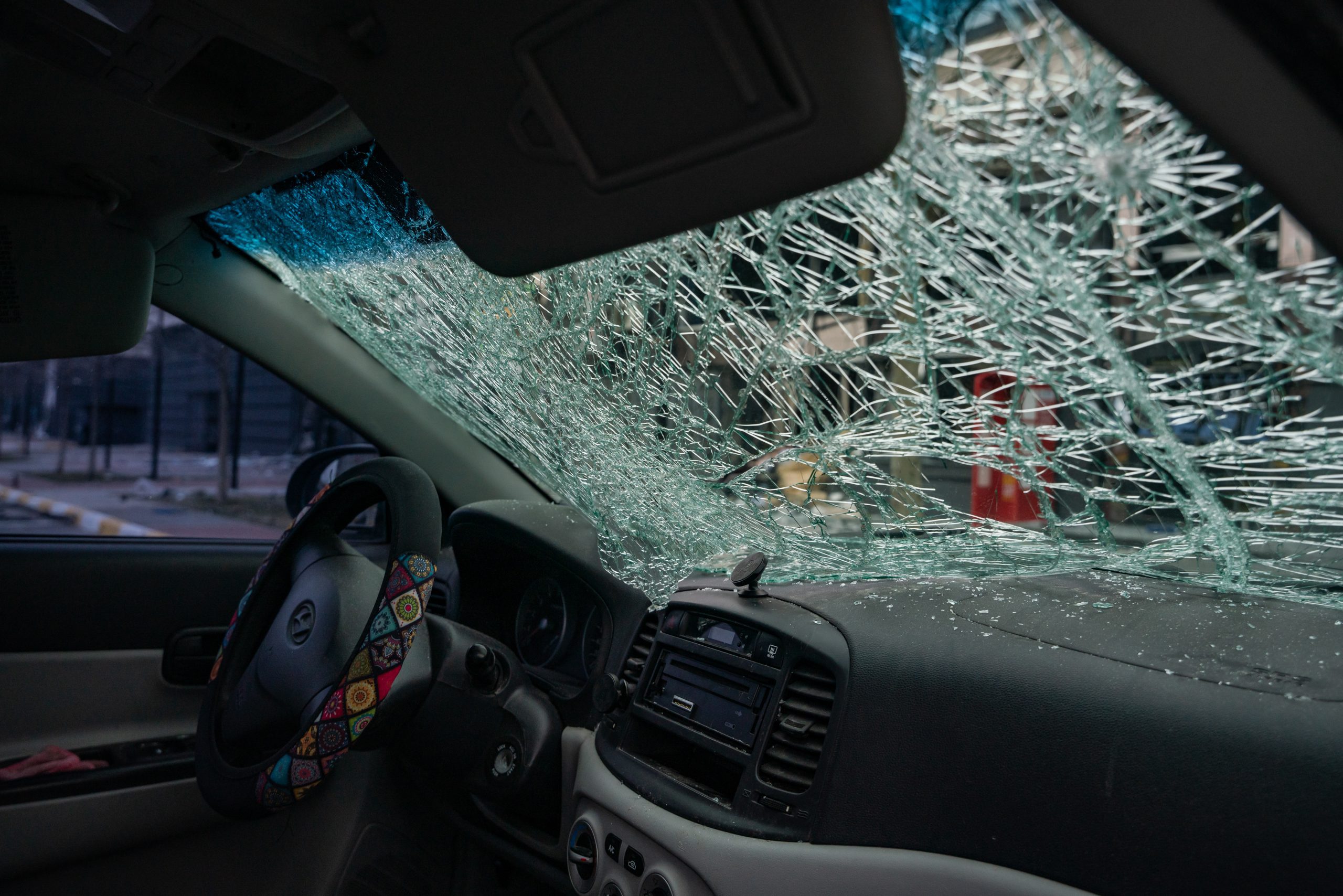 Szkło z rozbitego cywilnego samochodu. Rosjanie ostrzelali samochód na środku ulicy.