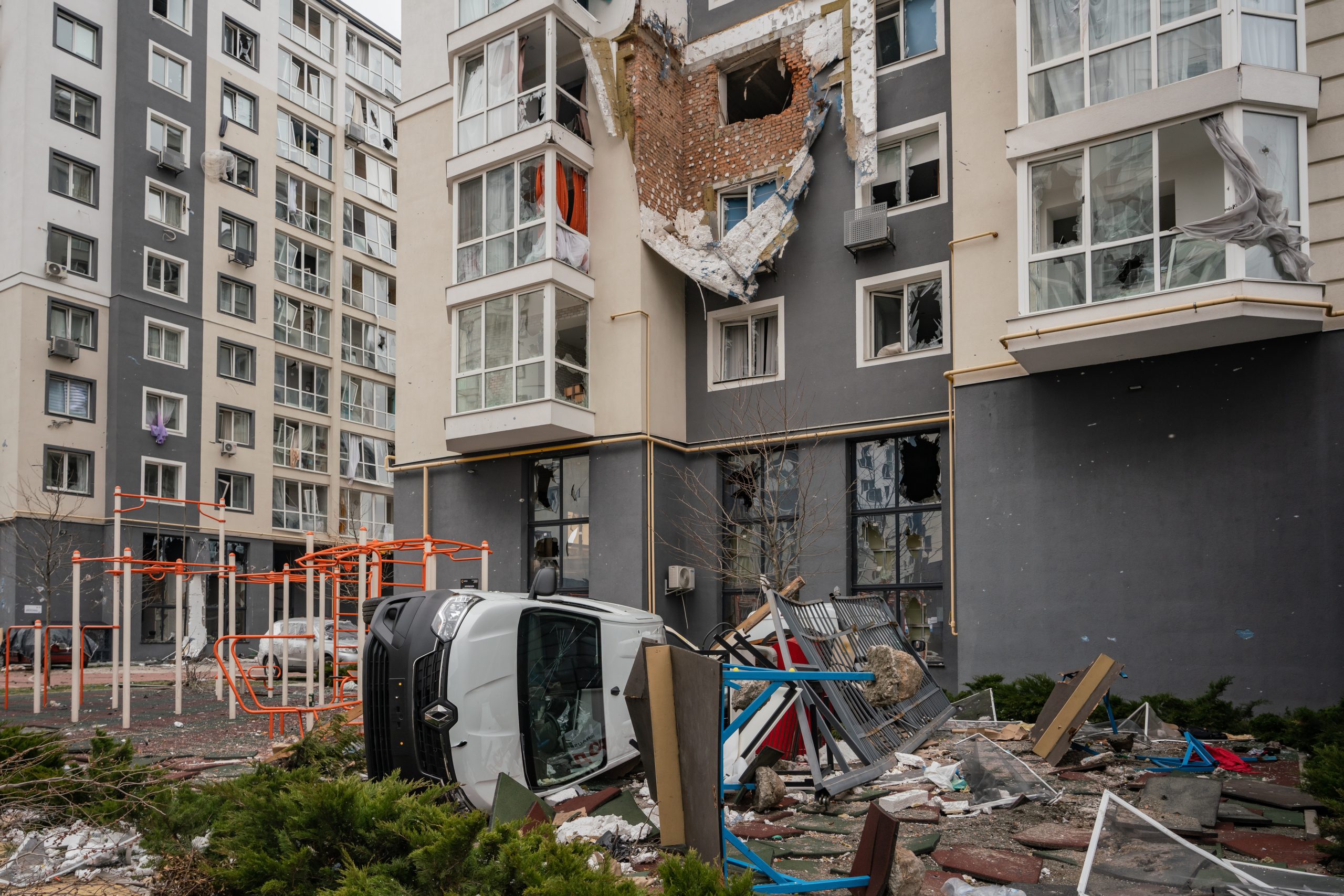 Zniszczone samochody i budynek kompleksu mieszkalnego w Buczy, w którym stacjonowało rosyjskie wojsko.
